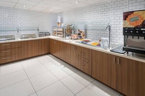 A modern kitchen with a white tiled backsplash, wooden cabinets, and a breakfast bar with various food items and a coffee machine. - King Studio Near Atek Pest Control Inc MIA (Miami)
