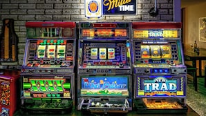 A row of slot machines with various game themes and a sign above stating "It's Miller Time". - Arcade + Hot Tub Retreat Sauna Near WPAFB (Dayton)