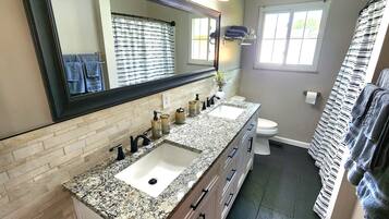 Une salle de bain avec deux lavabos, un grand miroir et des toilettes.