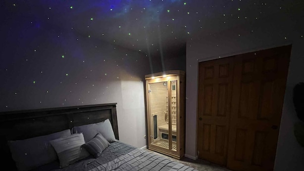 A bedroom with a bed, a wardrobe, and a starry ceiling. - Arcade + Hot Tub Retreat Sauna Near WPAFB (Dayton)