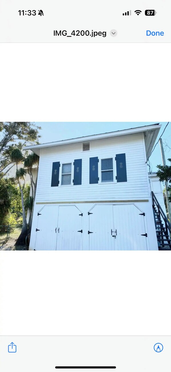 A white building with two windows and a garage door. - Indian River Getaway (Fort Pierce)