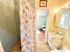 A bathroom with a shower curtain featuring sea life patterns, a sink with toiletries, and a mirror above it. - Indian River Getaway (Fort Pierce)
