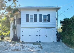 A two-story house with a garage, a tree in front, and a clear sky. - Indian River Getaway (Fort Pierce)