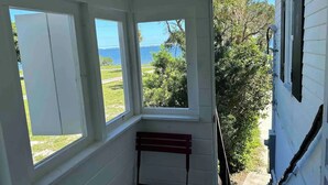 A room with three large windows offering views of a body of water and greenery.