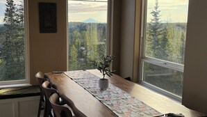 A dining area with a wooden table, chairs, and a potted plant. - Amazing view, perfect for large families, central Kenai Peninsula location! (Soldotna)
