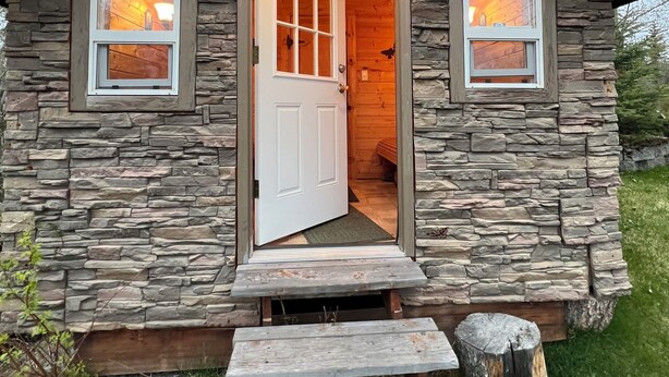 A stone cabin with a wooden door and two windows, each with a light inside. - Amazing view, perfect for large families, central Kenai Peninsula location! (Soldotna)