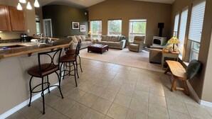 A spacious kitchen with a central island, a dining area with bar stools, a living room with a sofa and chairs, and a fireplace. - Amazing view, perfect for large families, central Kenai Peninsula location! (Soldotna)