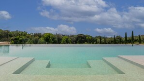 Ein klares, blaues Schwimmbecken mit Stufen, umgeben von Bäumen und einem Zaun.