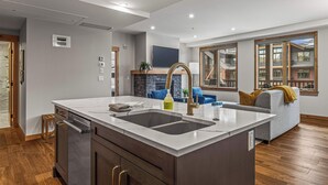 A modern kitchen with a large island, built-in appliances, and a view to the living area. - Spring Creek Vacations 2 BR Premier Condo 315TM (Canmore)