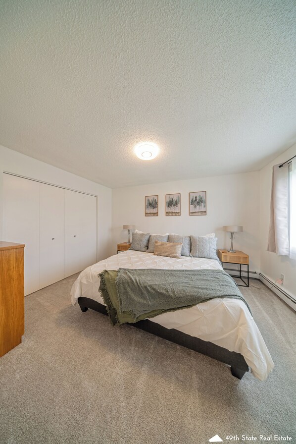 A bedroom with a bed, a wardrobe, a nightstand, and a lamp.