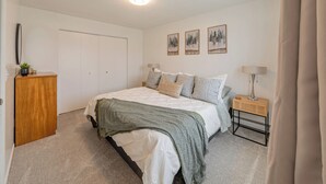A bedroom with a bed, a nightstand, a lamp, a dresser, and a closet. - Your Nordic Retreat (Anchorage)