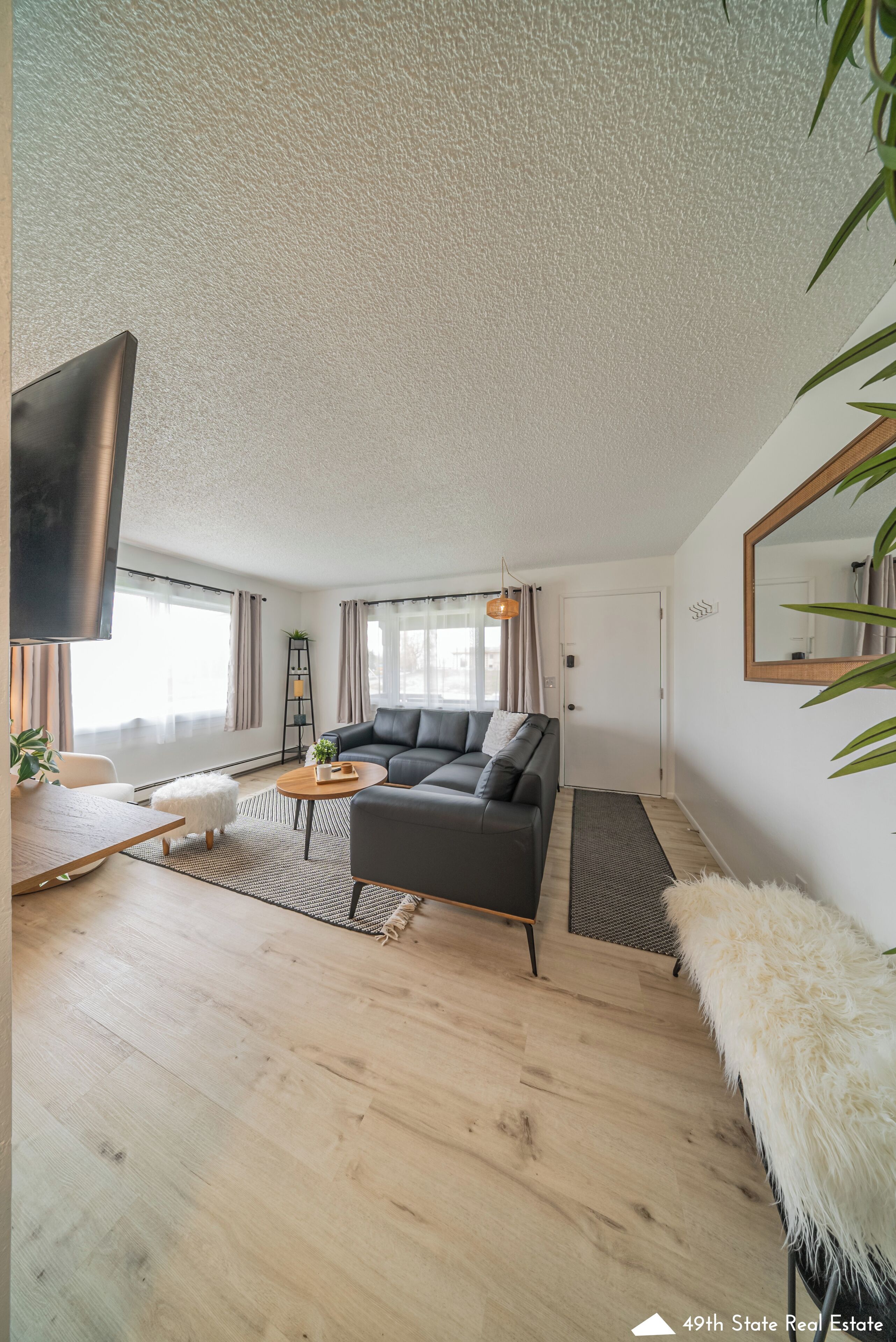 Una sala de estar moderna con un sofá modular, un televisor de pantalla plana y un espejo grande.