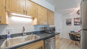 A modern kitchen with wooden cabinets, stainless steel appliances, and a black countertop. - Your Nordic Retreat (Anchorage)