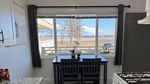 Una cocina con una mesa, sillas, estufa y vistas al exterior.