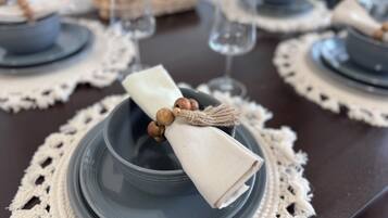 Una mesa servida con platos azules, servilletas blancas y vasos transparentes.