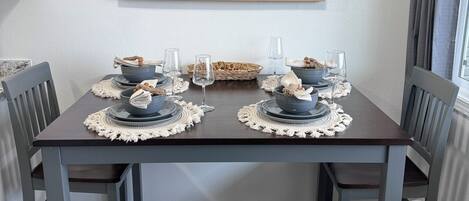 A dining table set with blue plates, bowls, and glasses, surrounded by chairs.