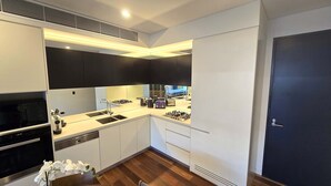 Una cocina moderna con armarios blancos, encimera negra y estufa integrada.