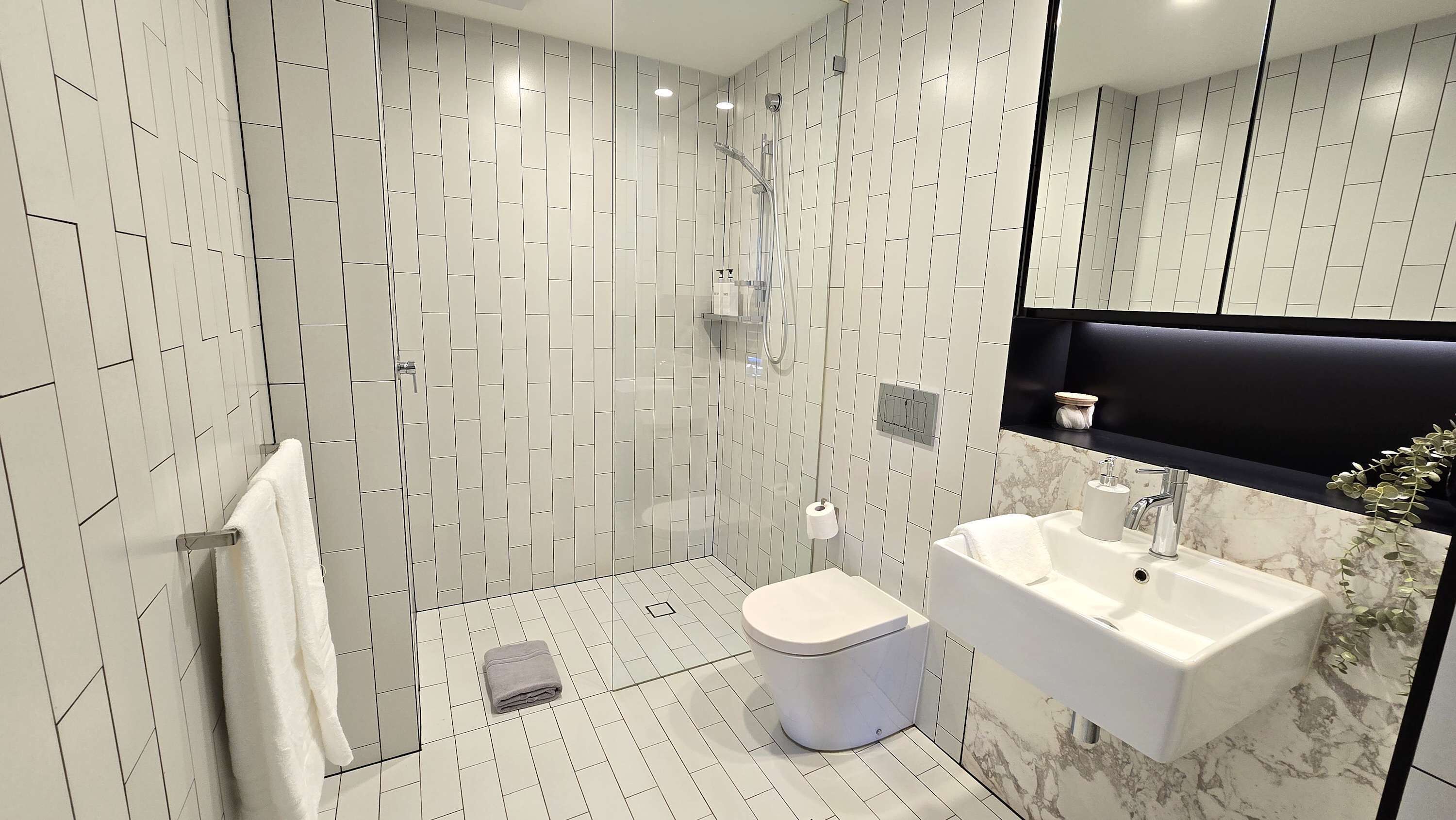 Une salle de bain moderne équipée d’une douche, de toilettes et d’un lavabo.