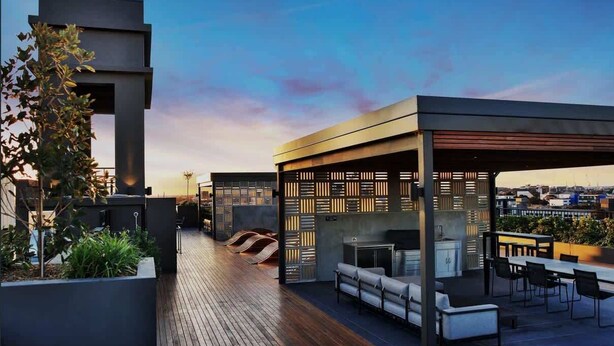 Una terraza en la azotea con cocina exterior moderna, zona de estar y vistas del horizonte de la ciudad.