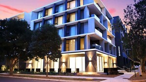 Un edificio moderno de varios pisos con balcones, grandes ventanales y una fachada bien iluminada.