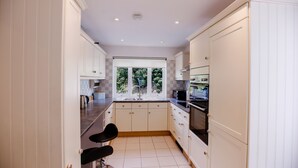 Une cuisine moderne avec des meubles blancs, une grande fenêtre et un tabouret de bar noir.