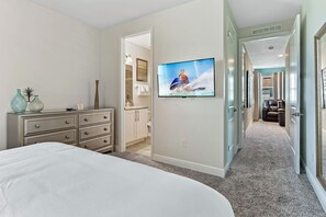Un dormitorio con una cama grande, un aparador y un televisor montado en la pared.