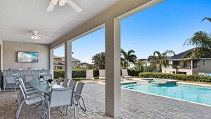 A covered outdoor area with a pool, dining tables, and chairs. - 8BR Modern Family Villa • Game Room • Near Disney (Kissimmee)