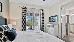 A hotel room with a large bed, a TV, a balcony with a pool view, and a kitchenette. - 8BR Modern Family Villa • Game Room • Near Disney (Kissimmee)