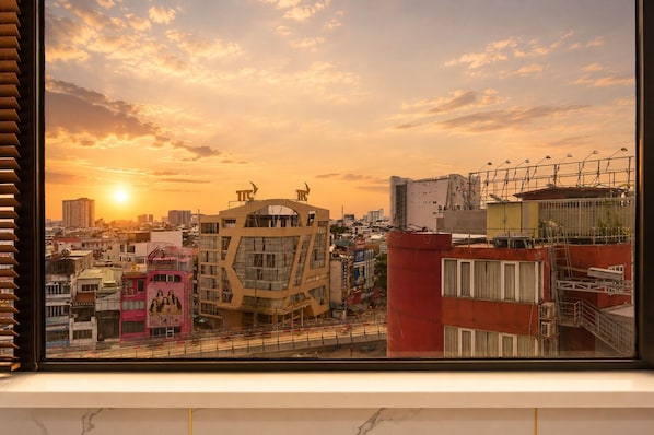 Un paisaje urbano con un edificio destacado de diseño angular único, cielo despejado y el sol poniéndose al fondo.