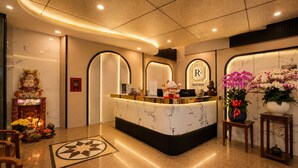 Een hotel receptie met een marmeren balie, een Boeddha beeld en een Red Sun logo.