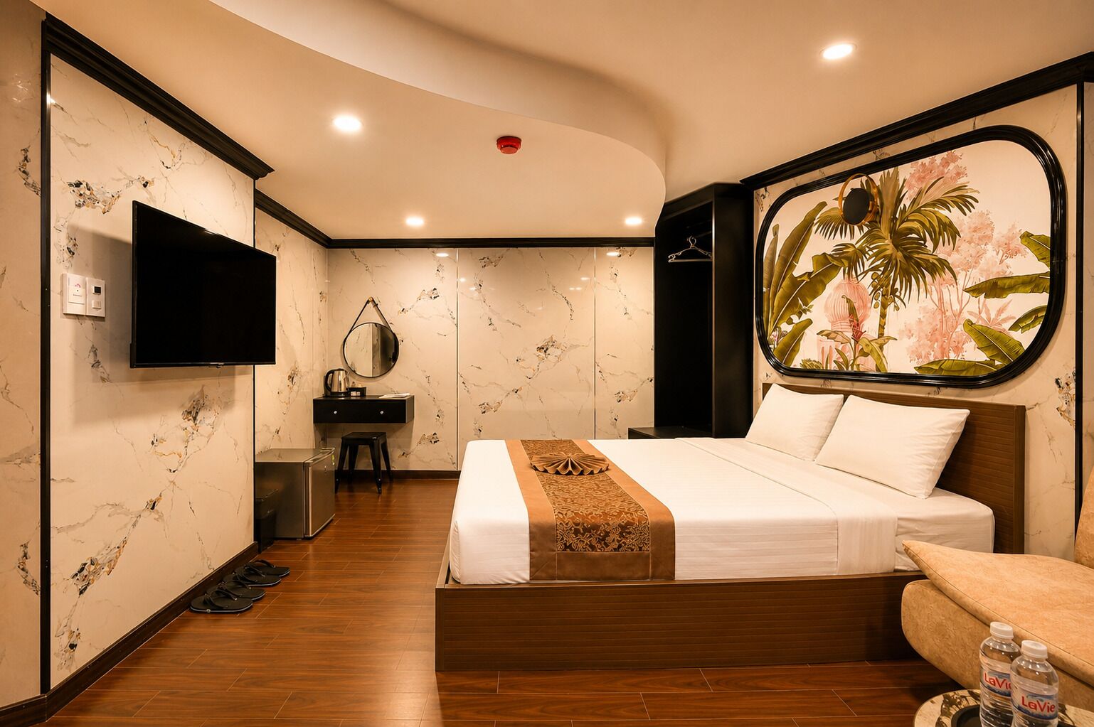 A hotel room with a bed, a desk, a mirror, a television, and a large window with a tropical view.