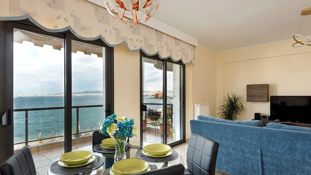 Un comedor con mesa de vidrio, sillas y vista al mar.