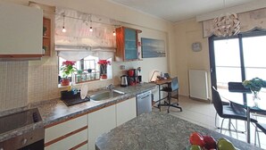 Una cocina moderna con lavavajillas incorporado, un comedor con mesa y sillas de vidrio, y un ventanal que proporciona luz natural.
