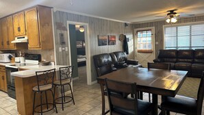 A spacious kitchen with wooden cabinets, a dining area with a large table and chairs, and a living room with a leather couch. - Fishing camp in Falgout Canal Marina! (theriot)