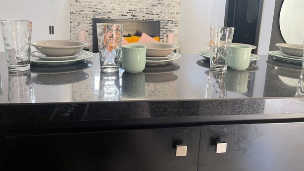A dining area with a black countertop, white plates, and clear glassware. - Cozy Studio Apartment.  Pet Friendly! (Sayulita)