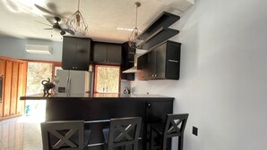 A modern kitchen with dark cabinetry, a central island with bar seating, and pendant lighting. - Cozy Studio Apartment.  Pet Friendly! (Sayulita)