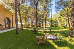 An outdoor patio area with tables and chairs, surrounded by trees.