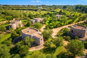 A series of stone structures with flat roofs, surrounded by lush greenery and a clear sky.