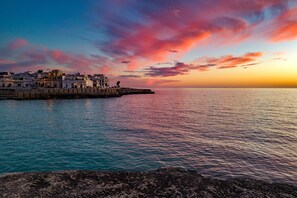 A coastal town with buildings along the waterfront, a clear sky, and calm sea.
