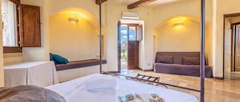 Un dormitorio con cama, un banco, un sofá y una zona de lectura con una revista.