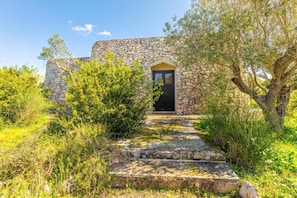 A stone building with a black door and a stone staircase leading up to it.