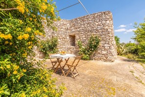 A stone building with a table and chairs in front, surrounded by greenery and flowers. - Pagliara Il Morige 5 In The Countryside, Galatone, Italy (Galatone)