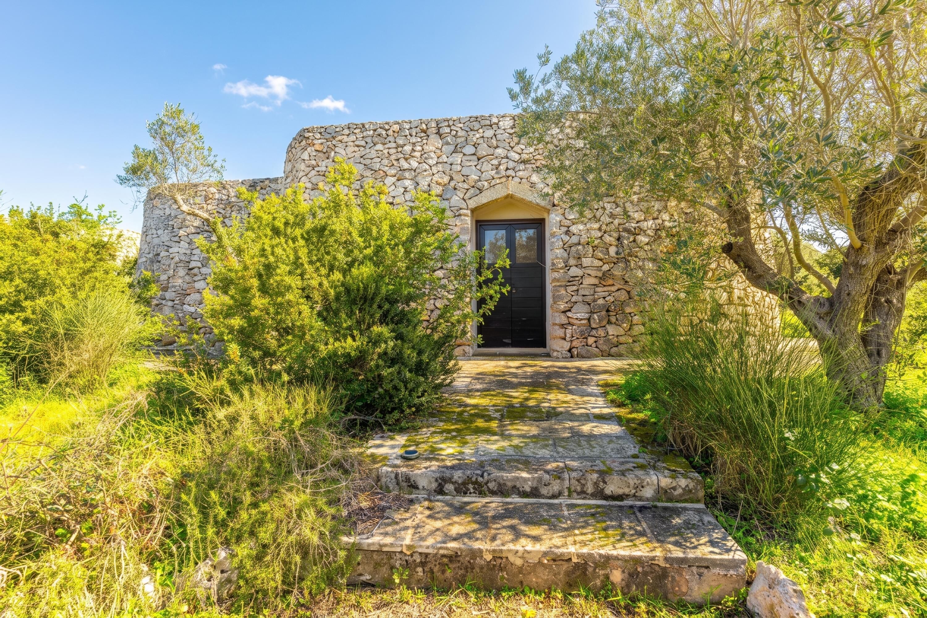 A stone building with a black door and a stone staircase leading up to it.