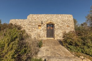 Un bâtiment en pierre avec une porte centrale et une petite fenêtre.