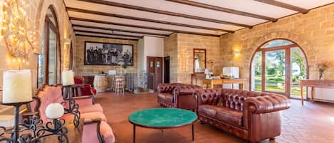 A spacious living area with a stone wall, a fireplace, a large leather sofa, and a dining area with a table and chairs.