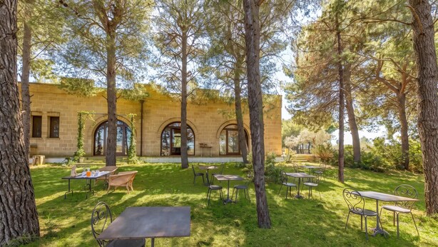 An outdoor patio with tables and chairs, surrounded by trees and a building with arched windows. - Pagliara Il Morige 2 In The Countryside, Galatone, Italy (Galatone)