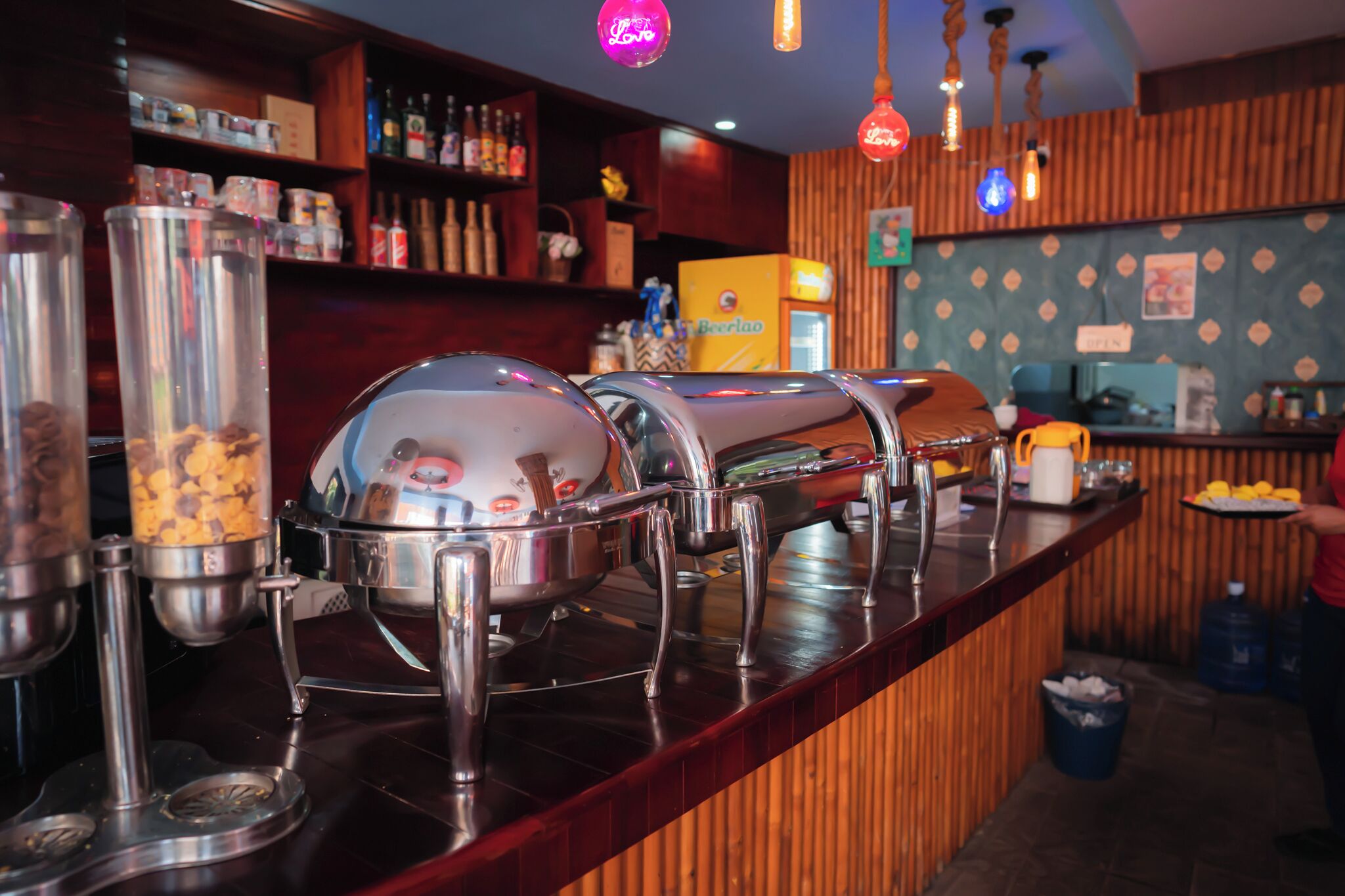 Un buffet proposant différents plats présentés dans des récipients variés, ainsi qu’un distributeur de boissons.