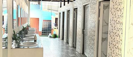 A hallway with tiled flooring, a reception area with a counter and plants, and patterned walls.