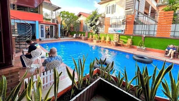Un área de piscina con sillones de descanso y zona de comedor.