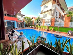 Un espace piscine avec des chaises longues et un coin repas.